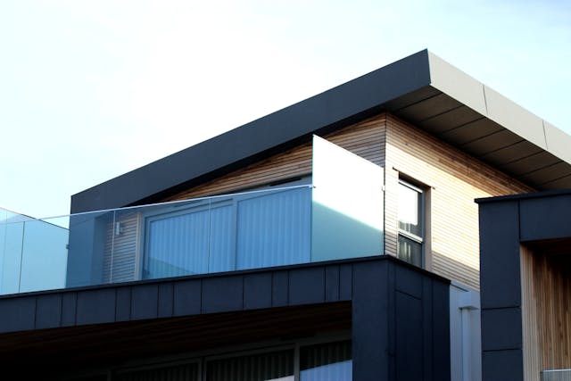 Een modern appartementencomplex met verschillende huurwoningen, omgeven door groen. Op de voorgrond staat een jong stel dat naar het gebouw kijkt, symbolisch voor de flexibiliteit en mogelijkheden die huurhuizen bieden voor verschillende levensfasen.